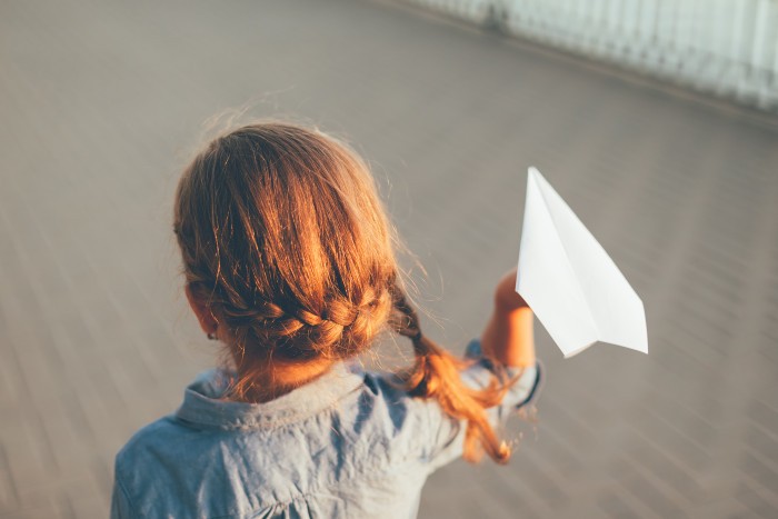 girl playing with toy paper airplane