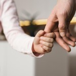 little girl holding hands with father