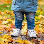 child wearing jeans standing dry autumn leaves